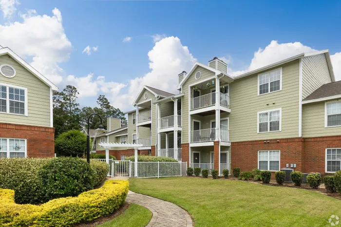 Beautiful contemporary apartment building with charming balconies, lush landscaping, and vibrant greenery under a clear blue sky.