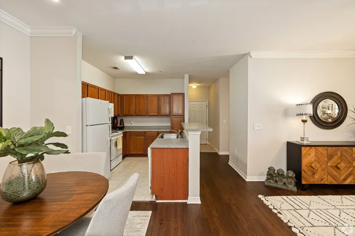 Elegant apartment interior featuring a cozy kitchen with wooden cabinetry, a dining area with stylish decor, and warm wooden flooring for a modern, inviting atmosphere.