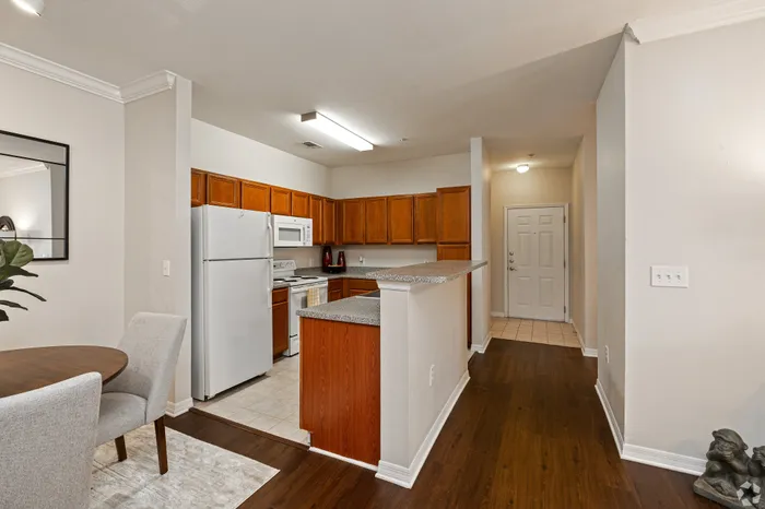 Inviting kitchen and dining area featuring warm wood cabinets, sleek appliances, and elegant hardwood flooring, perfect for cozy meals and gatherings.