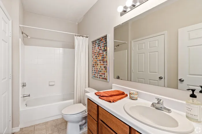 Modern bathroom featuring sleek white tiles, contemporary vanity with elegant fixtures, and vibrant decor accents.