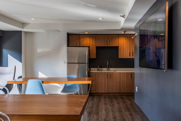 Modern open-concept kitchen with sleek wooden cabinetry, stainless steel appliances, and a cozy dining area with stylish blue chairs.