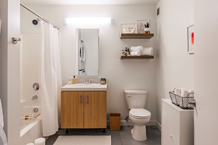 Modern bathroom with sleek vanity, white tiles, cozy lighting, and elegant shelving for a stylish apartment vibe.