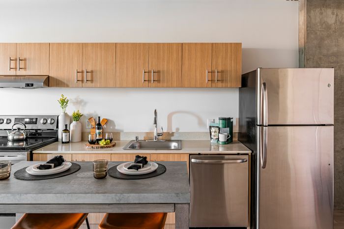 Modern kitchen with sleek wooden cabinets, stainless steel appliances, and elegant countertop dining setup.