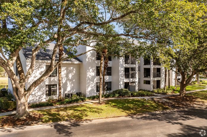 Charming apartment complex nestled among lush, mature trees, offering serene living with abundant natural light.
