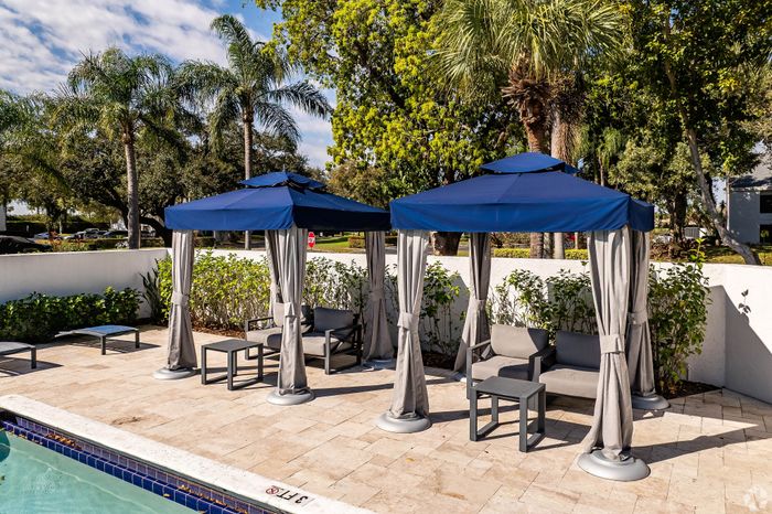 Luxury poolside oasis with elegant blue cabanas, surrounded by lush palm trees and vibrant greenery, offering perfect relaxation and comfort.