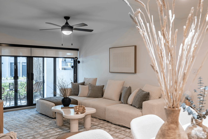 Chic living room with elegant beige sofa, modern coffee table, and natural decor, opening to a serene outdoor patio.