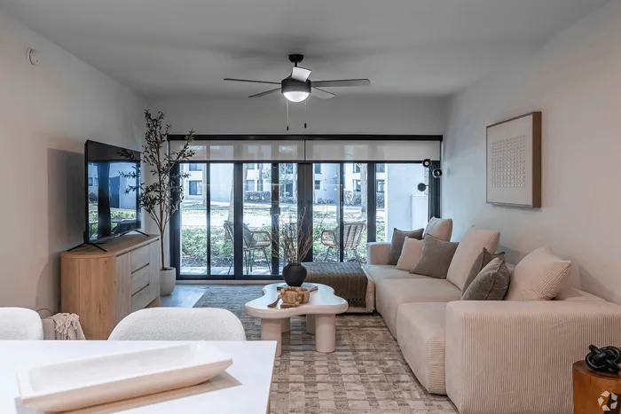 Modern living room with stylish decor, large sectional sofa, and expansive sliding glass doors opening to a serene patio view.
