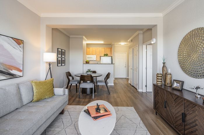 Inviting open-concept living and dining area with stylish decor, featuring a cozy gray sofa, chic dining set, and modern kitchen.