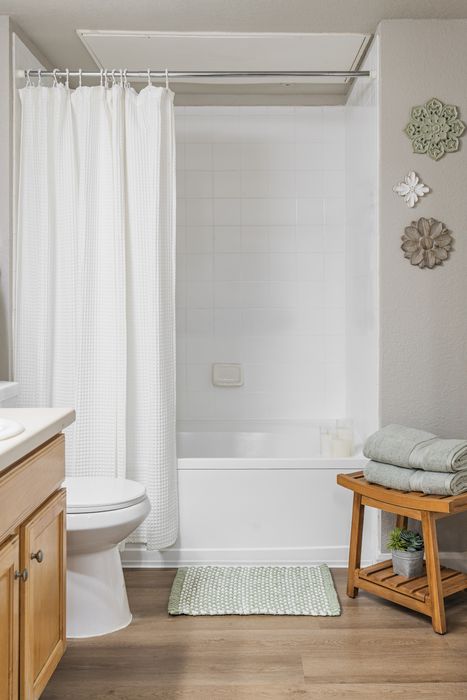 Inviting bathroom with elegant white tiles, cozy bathtub, and charming wooden decor for a serene ambiance.