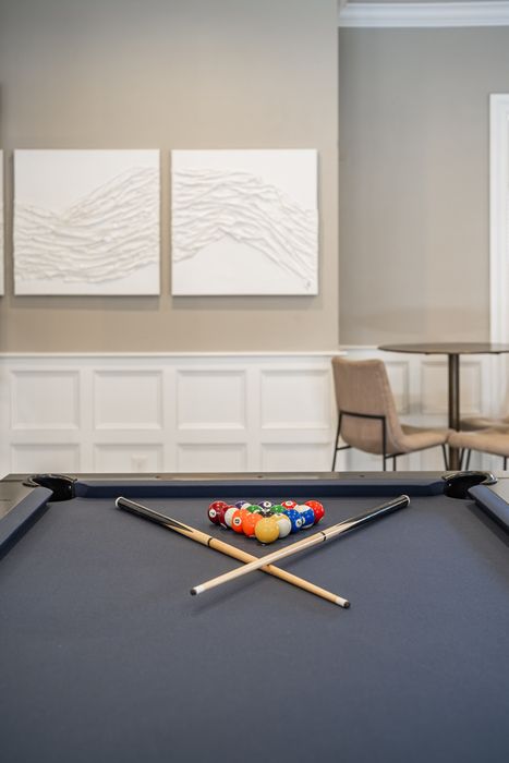 Chic and inviting game room with a stylish pool table set against modern wall art, perfect for leisure and entertainment.