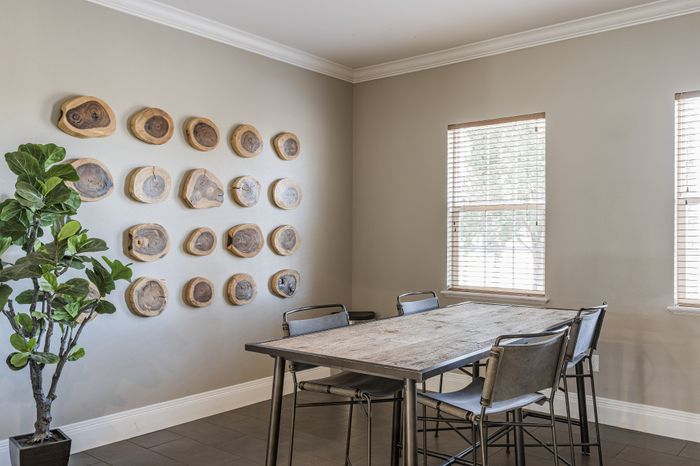Chic dining area with stylish wooden wall art, rustic table, and modern chairs, bathed in natural light.
