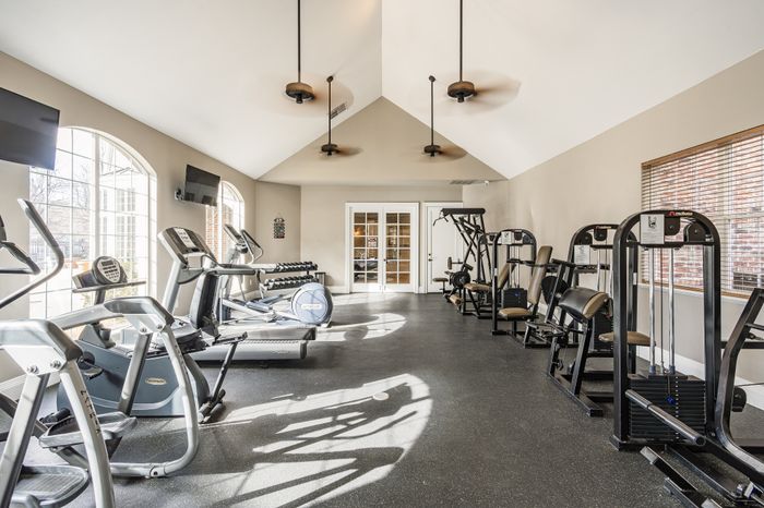 Bright, spacious fitness center with modern exercise equipment and natural lighting from large windows.