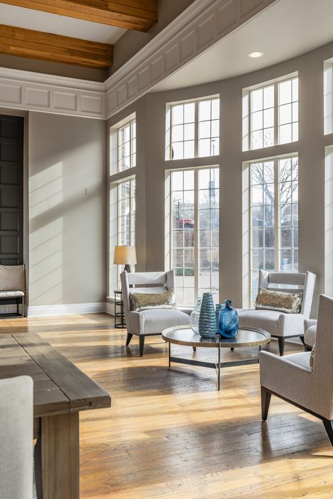 Bright and inviting living room with large windows, elegant furniture, and wooden floors, perfect for serene relaxation.