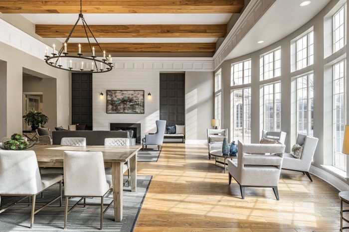 Luxurious living area featuring elegant wooden beams, large sunlit windows, and sophisticated modern decor.
