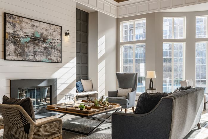Elegant living room with large windows, cozy seating, and modern fireplace, bathed in natural sunlight.