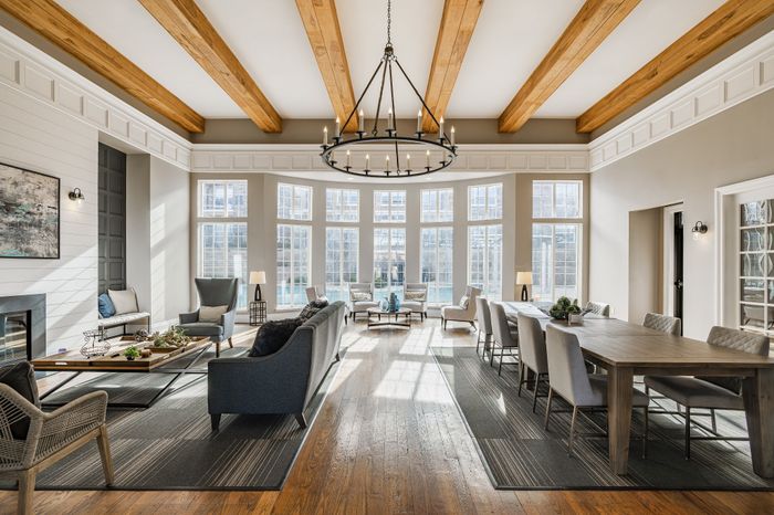 Elegant living and dining area featuring high ceilings with exposed wooden beams, large windows with abundant natural light, and stylish furnishings for a sophisticated ambiance.