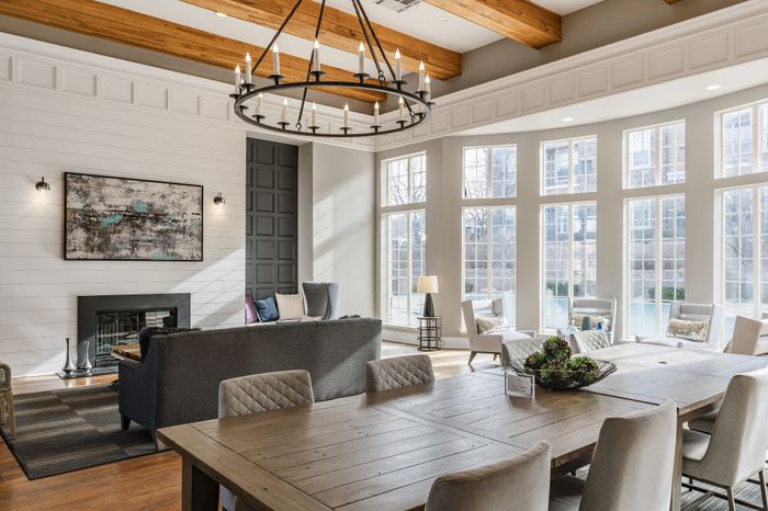 Bright, inviting living and dining area with large windows, wooden beams, and a modern chandelier, perfect for family gatherings.