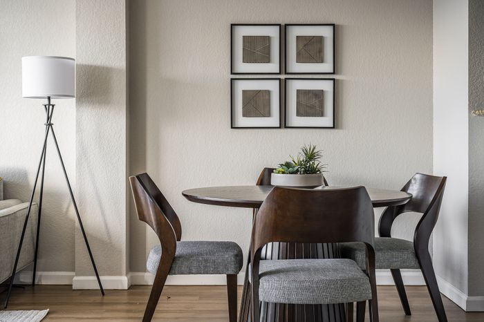 Chic dining area with a modern round wooden table, elegant chairs, and contemporary wall art, enhanced by soft natural lighting.
