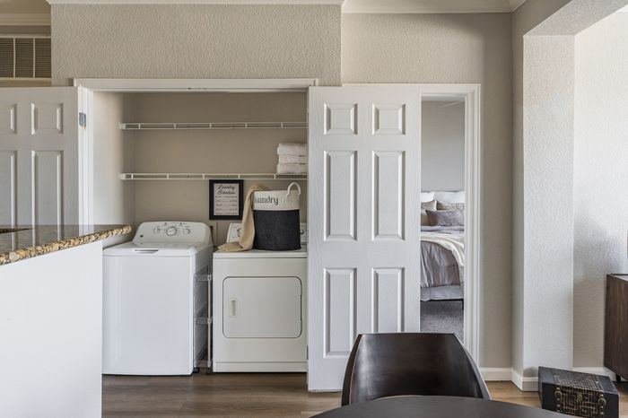 Charming apartment featuring an in-unit laundry area with a washer and dryer, adjacent to an inviting bedroom. Perfect for convenient and stylish living.