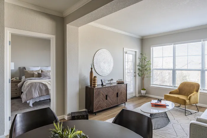 Cozy living space featuring a modern dining area, elegant bedroom entry, stylish decor, and large windows with natural light.