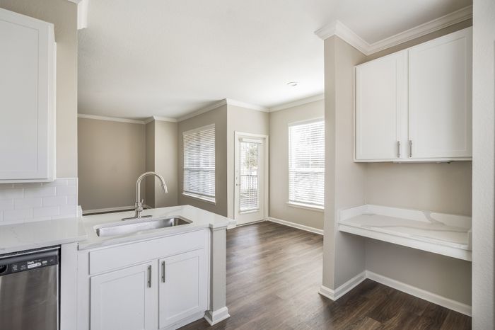 Bright and modern kitchen with sleek white cabinetry, elegant white countertops, and rich wood flooring, offering an inviting and airy atmosphere.