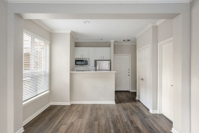 Bright and inviting kitchen entryway with modern cabinetry, sleek stainless steel appliances, and elegant wood flooring.