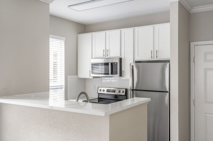 Modern kitchen with sleek stainless steel appliances, white cabinetry, and bright natural light.
