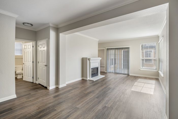 Bright and spacious living area with elegant wood flooring, a cozy fireplace, and large windows providing abundant natural light.
