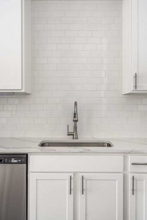 Modern kitchen featuring sleek stainless steel fixtures, elegant white cabinetry, and a stylish subway tile backsplash.