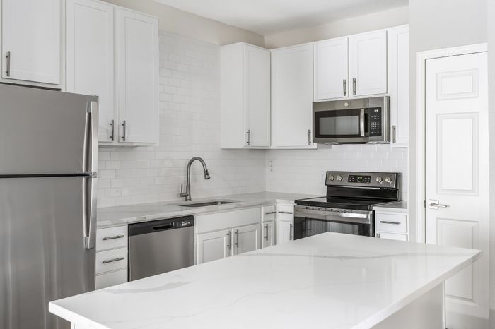 Modern kitchen with sleek white cabinetry, stainless steel appliances, and elegant marble countertops.