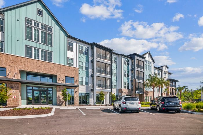 Modern apartment building with stylish design and spacious balconies under a clear blue sky.