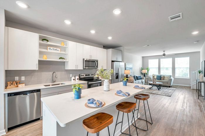 Modern open-concept kitchen and living area with sleek appliances, elegant decor, and abundant natural light.