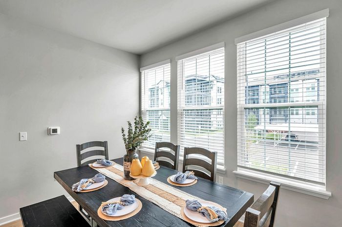 Bright dining area with large windows, featuring a chic black table set for four, accented with elegant decor and natural light.