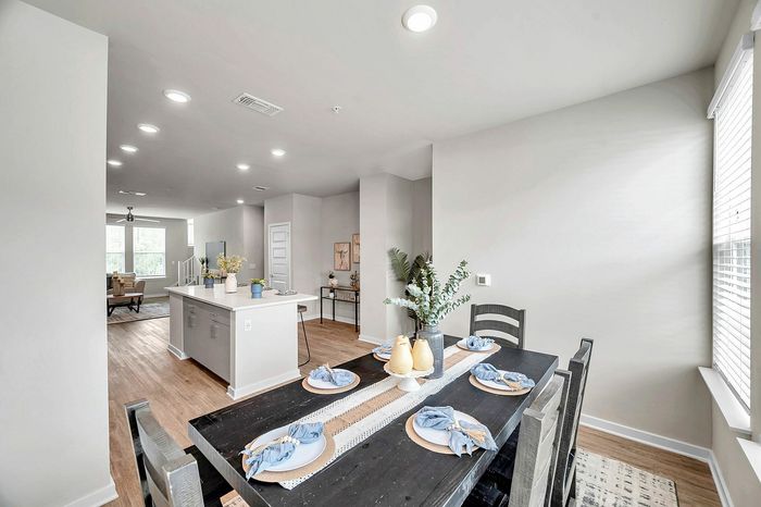 Bright open-concept living space with a modern kitchen island and elegant dining area, bathed in natural light.