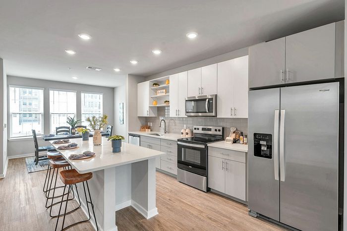 Modern kitchen with sleek stainless steel appliances, spacious island, and elegant dining area. Bright natural lighting enhances the clean, contemporary design.