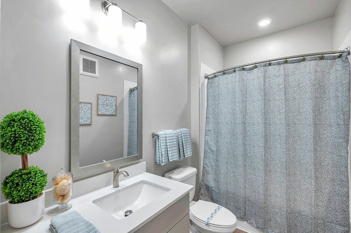 Elegant bathroom with modern fixtures, a stylish mirror, and soothing color palette, featuring plush towels and vibrant plant decor.
