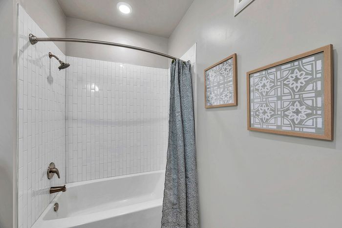 Modern bathroom with elegant white tile shower, stylish framed art, and a chic shower curtain.