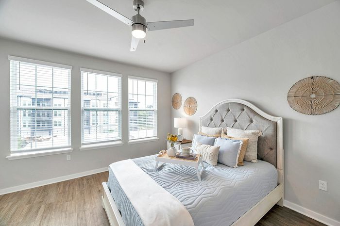 Bright and airy bedroom featuring elegant decor, a plush bed with soft cushions, and large windows offering scenic views.