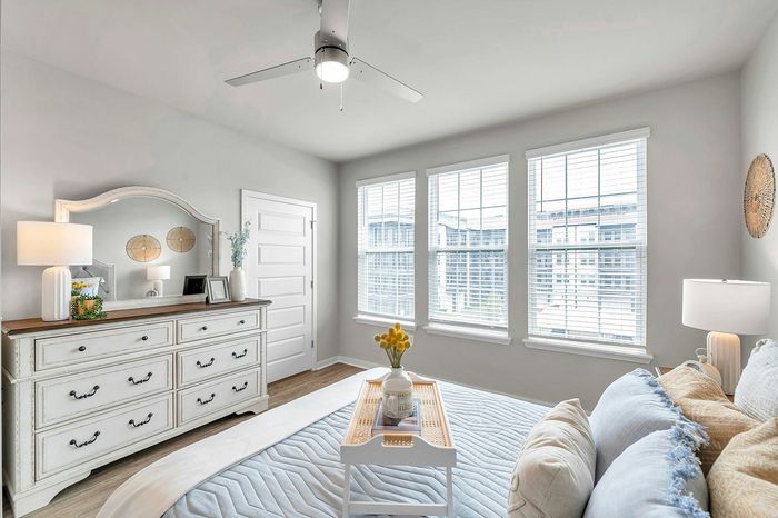 Bright and elegant bedroom with large windows, chic furniture, and stylish decor, perfect for a cozy retreat.
