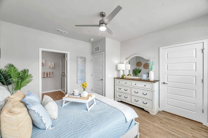 Bright and inviting bedroom featuring a stylish bed with cozy pillows, sleek dresser, and modern ceiling fan, complemented by soft natural light.