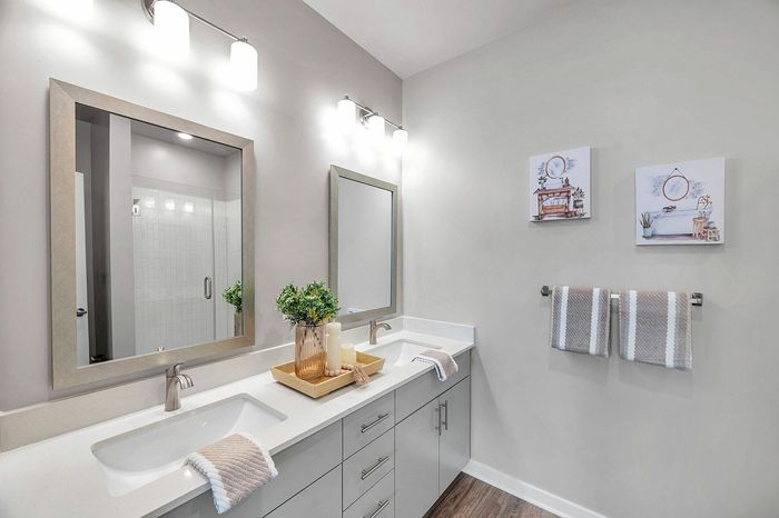 Elegant modern bathroom with dual sinks, stylish mirrors, decorative plants, and soft lighting for a serene atmosphere.