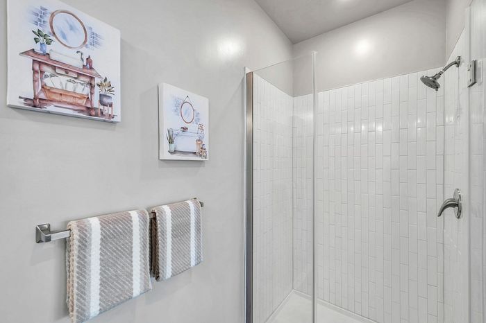 Modern bathroom with elegant glass shower, stylish wall art, and cozy towels enhancing the serene ambiance.