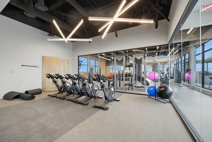 Modern fitness room with sleek exercise bikes, trendy lighting, and large windows for natural light.