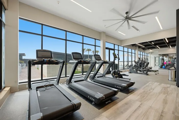 Modern fitness center with state-of-the-art treadmills, large windows, and bright, inviting space.