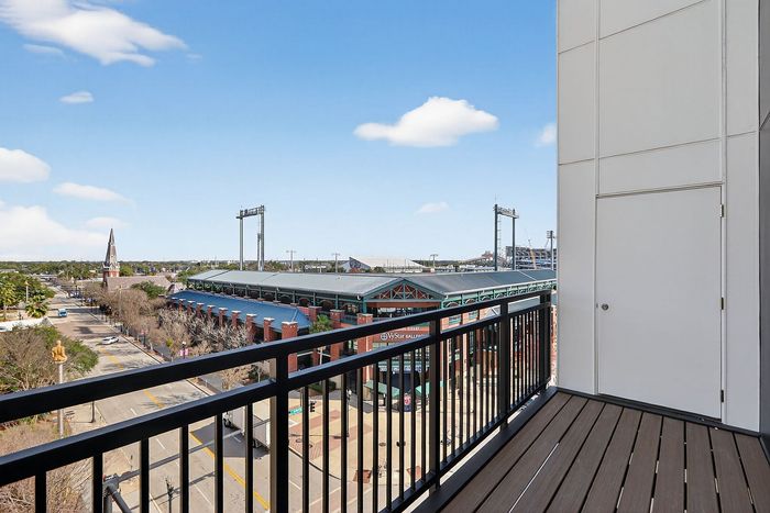 Chic apartment balcony with a stunning view of a stadium and cityscape, perfect for urban living.