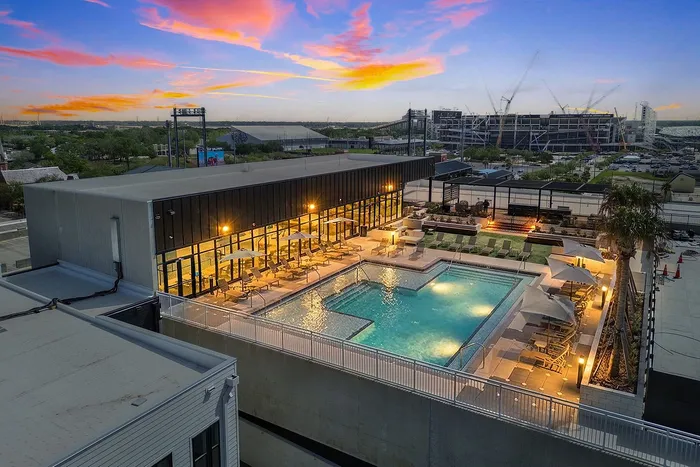 Luxurious rooftop pool with chic sun loungers and vibrant city view at sunset, ideal for relaxation and leisure.