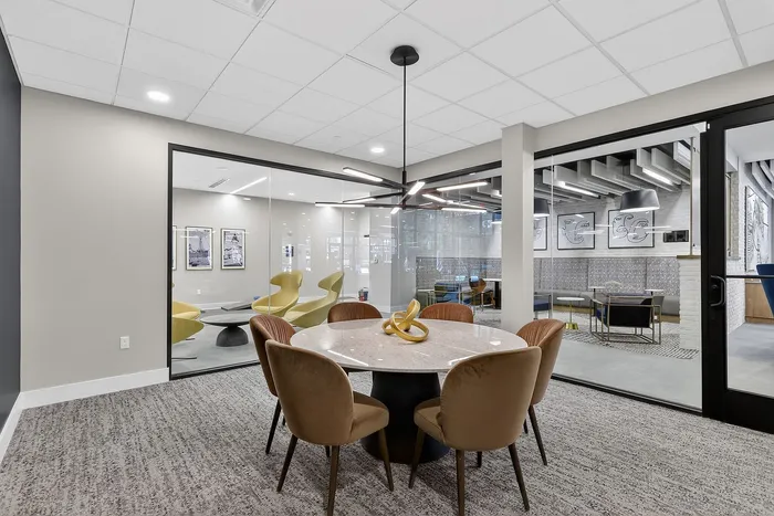 Modern communal area featuring stylish contemporary seating, a round marble table, and sleek lighting fixtures, ideal for meetings or social gatherings.