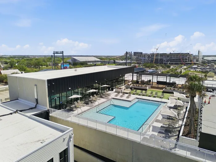 Luxurious rooftop pool with modern lounge area and sun umbrellas, offering a stylish urban view.