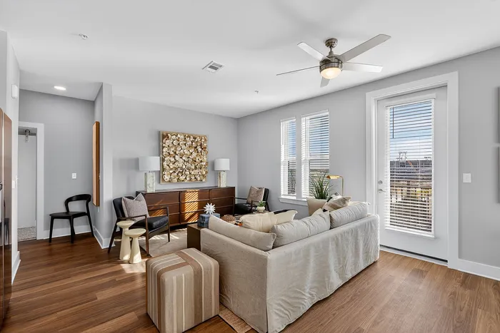 Bright and inviting living room with modern d&eacute;cor, featuring sleek hardwood floors and large windows for abundant natural light.