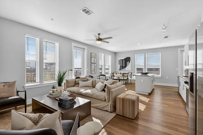 Bright and spacious modern apartment with open-concept living room, stylish dining area, and sleek kitchen featuring large windows and elegant decor.